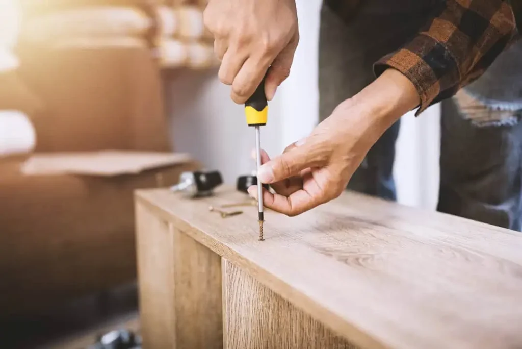 a person using a screwdriver to put a screw into a bookshelf which is laid on its side