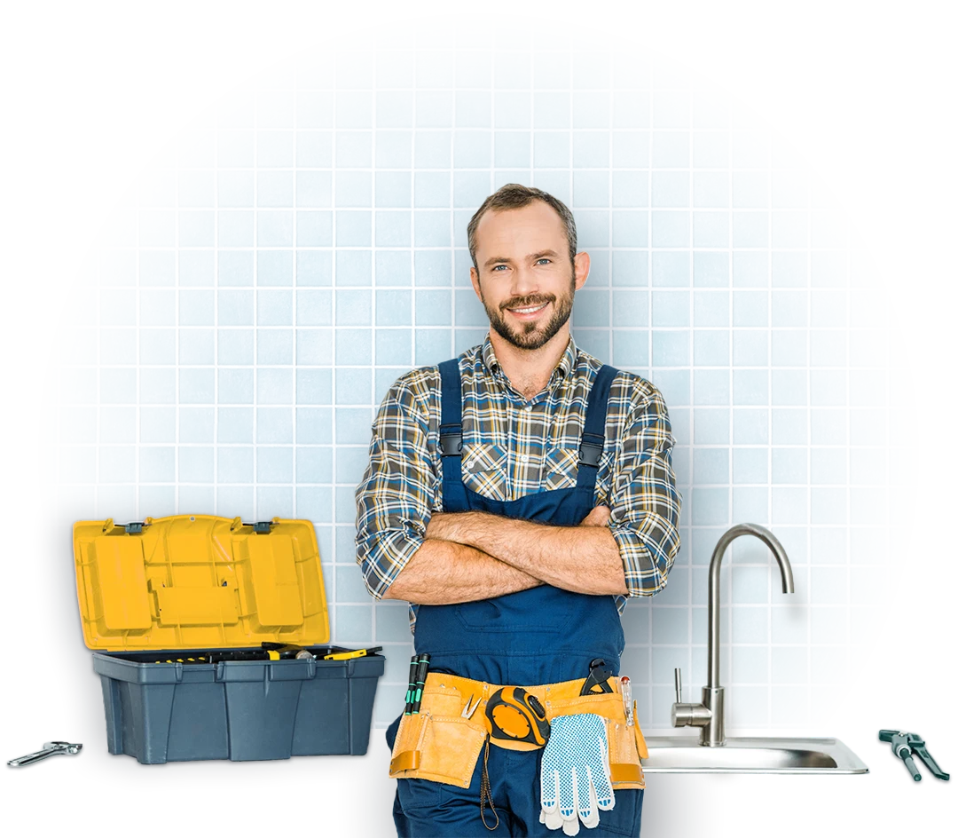 A handyman smiling and standing in front of a sink with his tool box next to him
