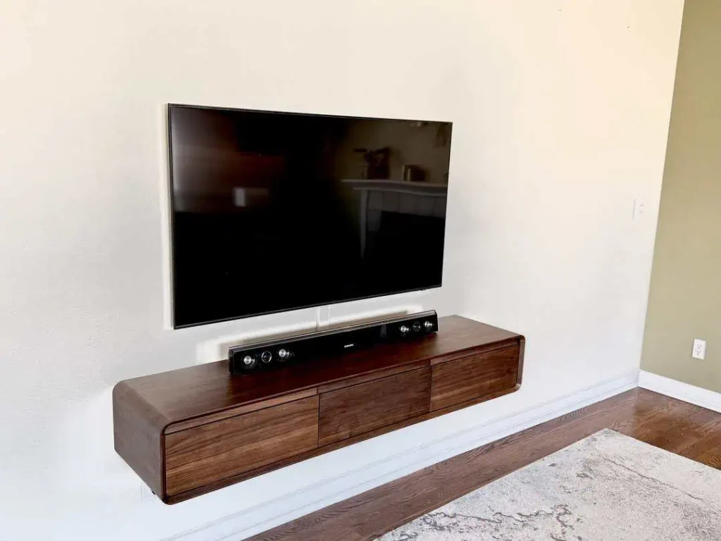 TV with cabinet below both installed on the wall by Seasons Home Solutions
