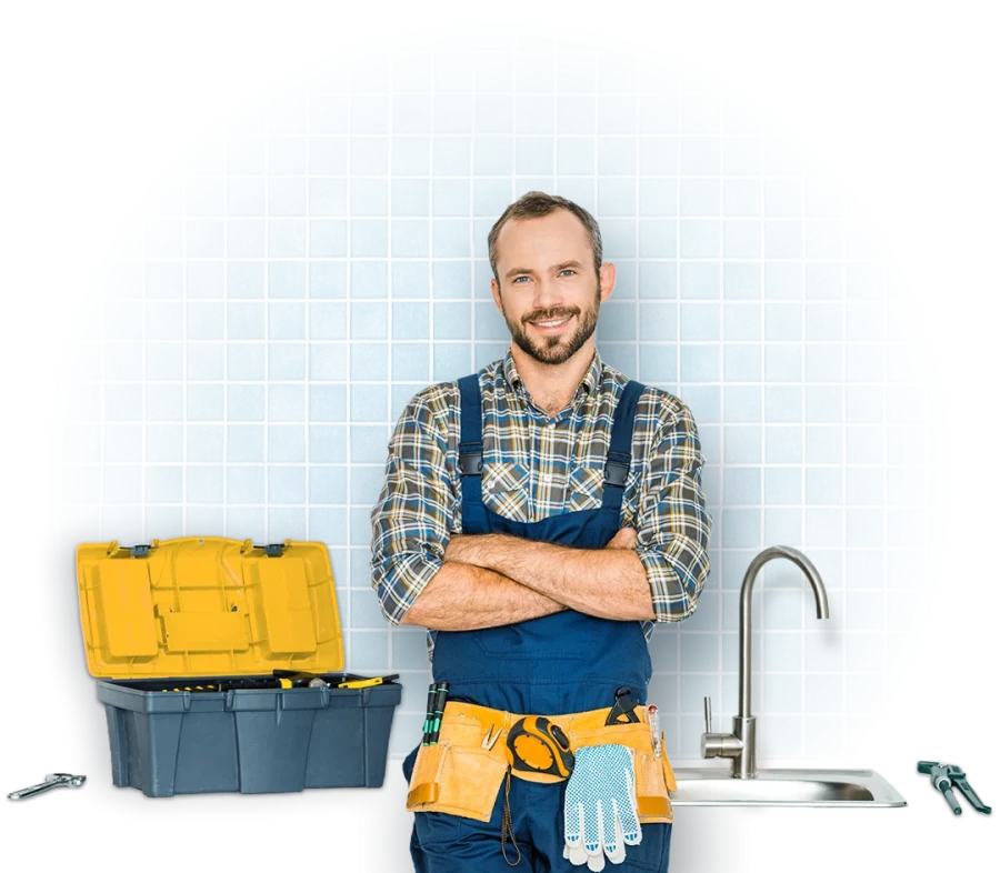 A handyman smiling and standing in front of a sink with his tool box next to him